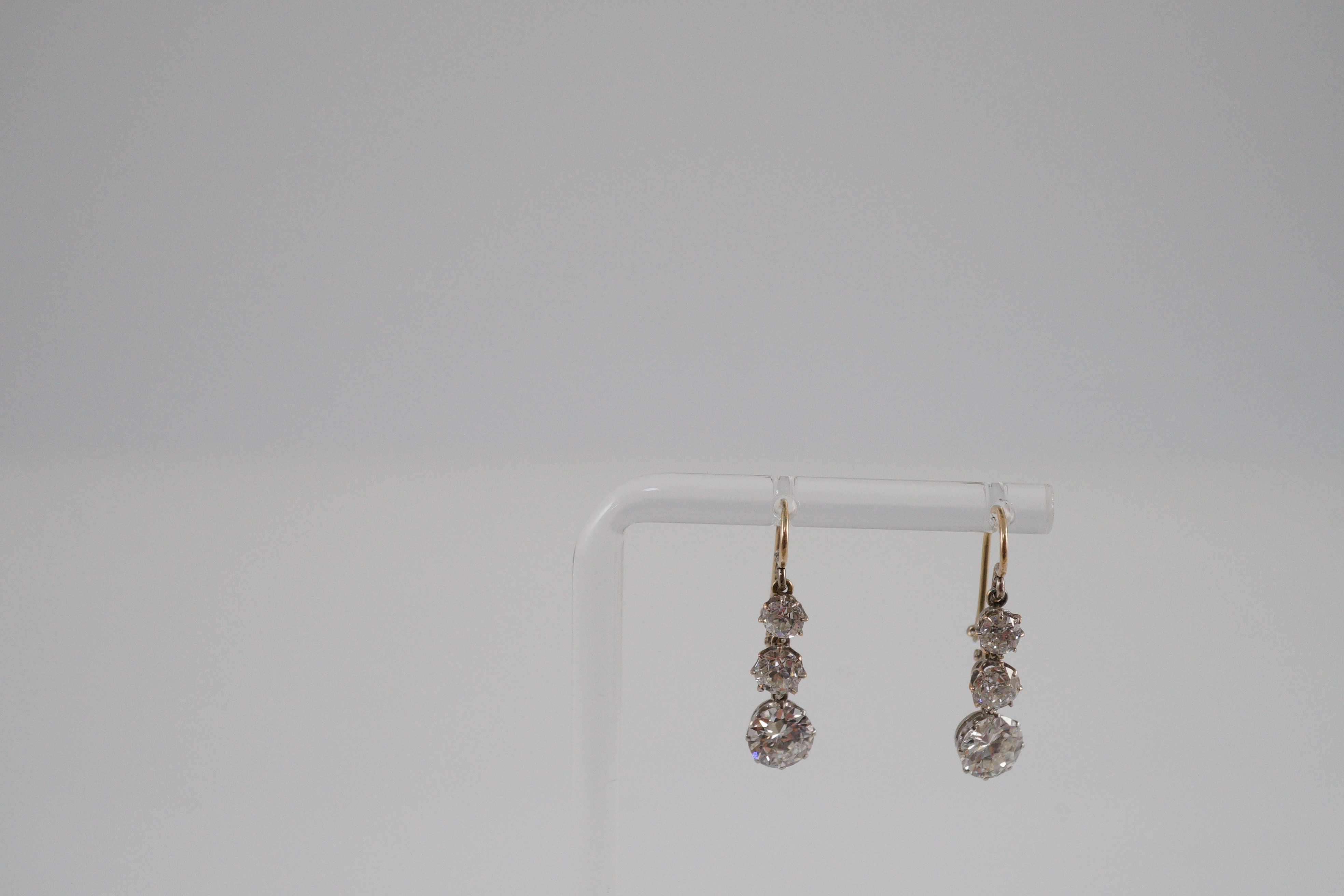 A pair of early to mid 20th century gold, platinum and graduated three stone diamond set drop earrings